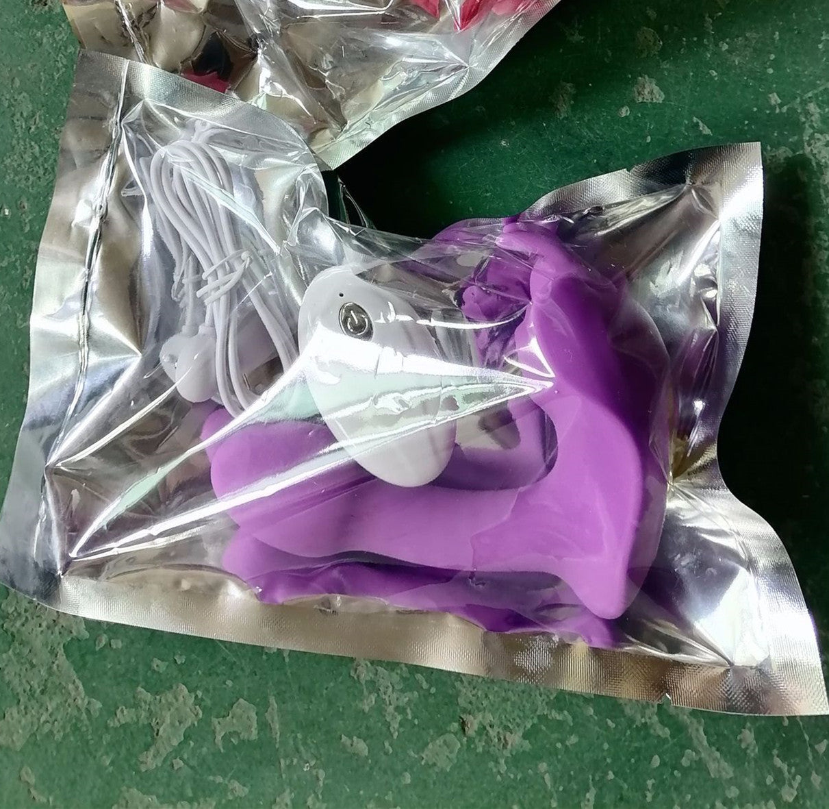 Image of a purple butterfly vibrator securely packaged in a silver metallic bag, including a white charging cable. The sealed packaging ensures hygiene and privacy, making it ideal for discreet shipping and storage. This visual highlights the product's ready-to-ship condition from a warehouse setting, emphasizing practicality in delivery and customer care.