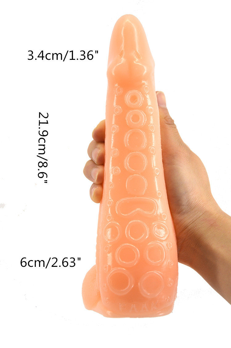 Hand holding a peach-colored silicone dildo with measurements on a white background